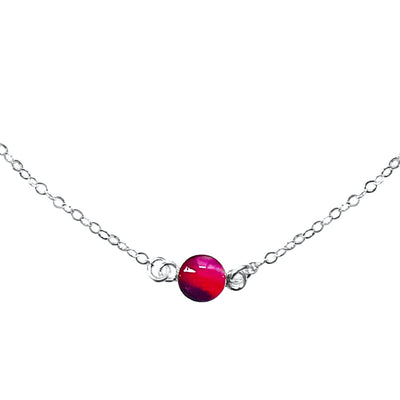 Close up of Circle of hope necklace with 6mm round red, pink and purple pendant with lupus cell image in resin on sterling silver chain necklace gives back