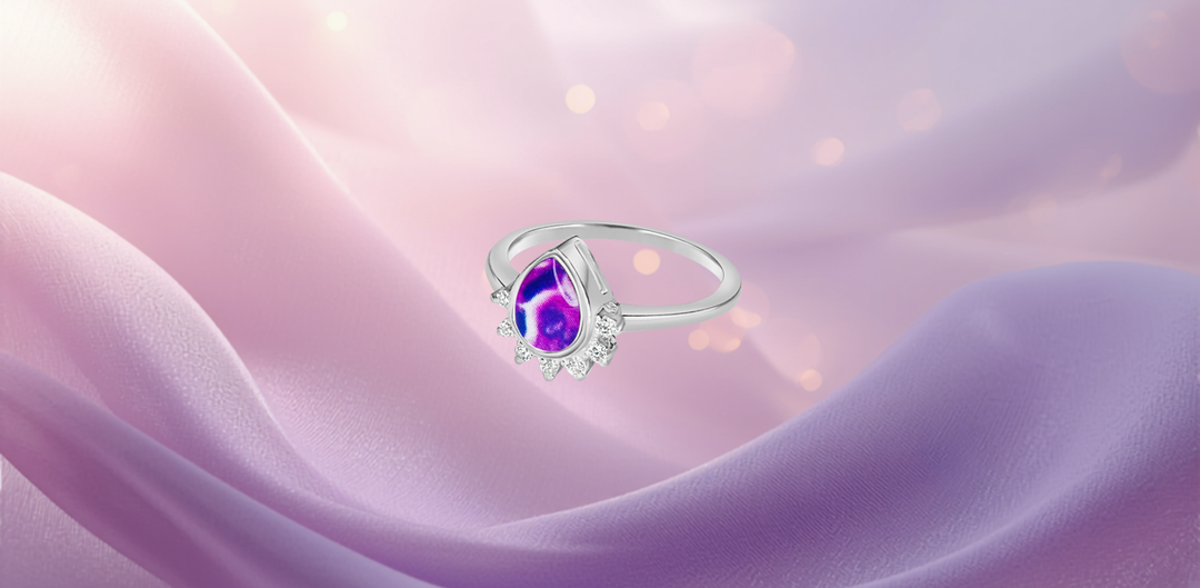 Sterling silver Halo of Hope ring with pancreatic cancer cell teardrop, set against a soft lavender silk background