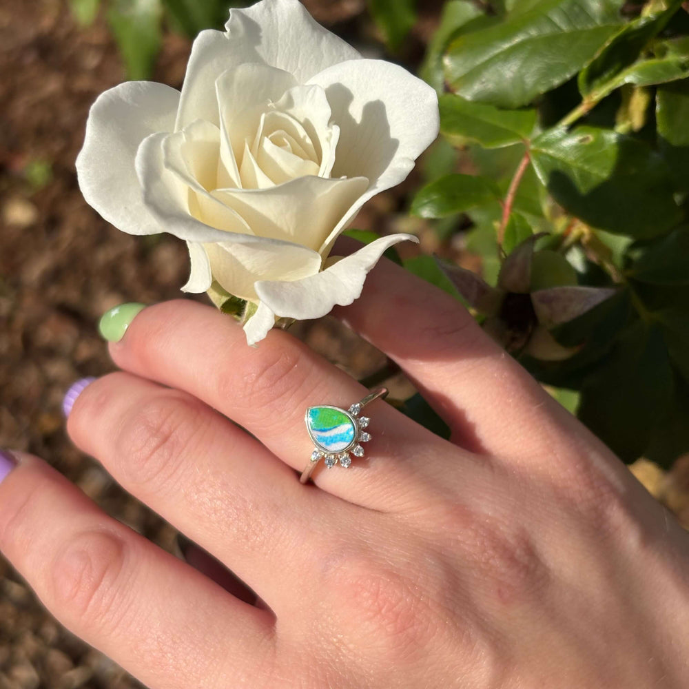 Sterling silver teardrop shaped ring with half halo of cubic zirconia stones and alzheimers cell image under resin pendant on model