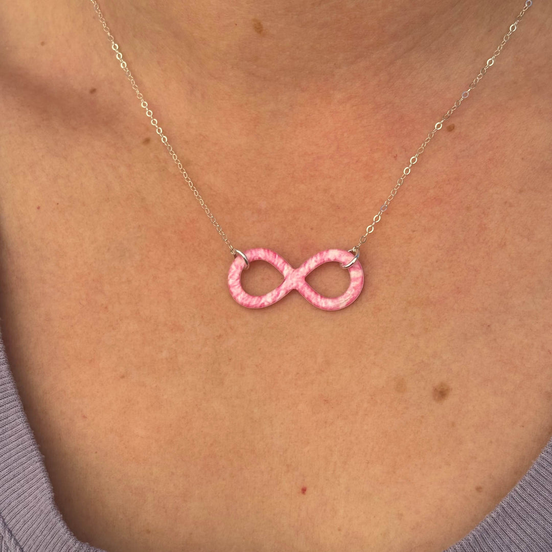 close up of model wearing pink breast cancer cell image infinity symbol pendant with resin and Sterling silver chain necklace