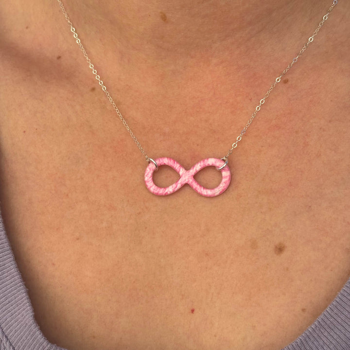 close up of model wearing pink breast cancer cell image infinity symbol pendant with resin and Sterling silver chain necklace