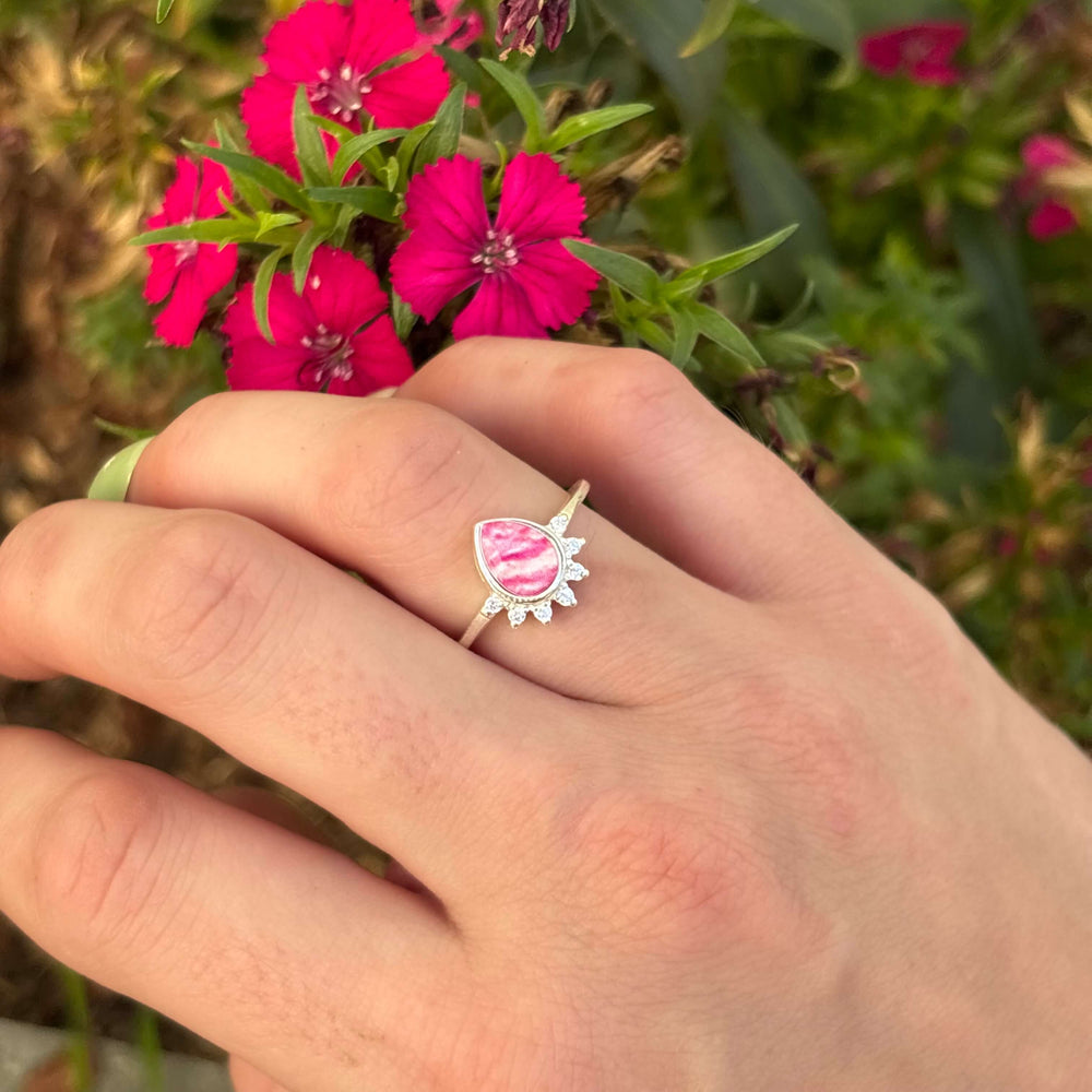 Sterling silver teardrop shaped ring with half halo of cubic zirconia stones and breast cancer cell image under resin pendant on model