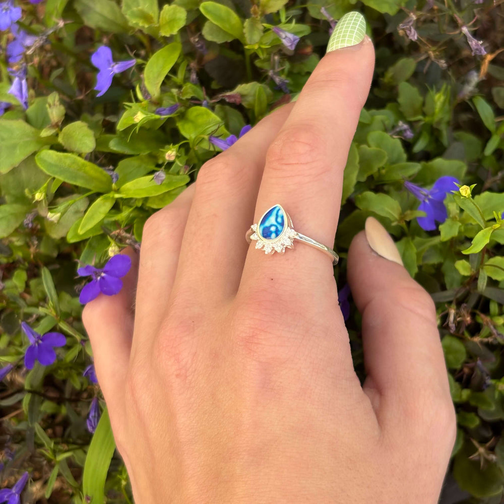 Sterling silver teardrop shaped ring with half halo of cubic zirconia stones and childhood cancer cell image under resin pendant model