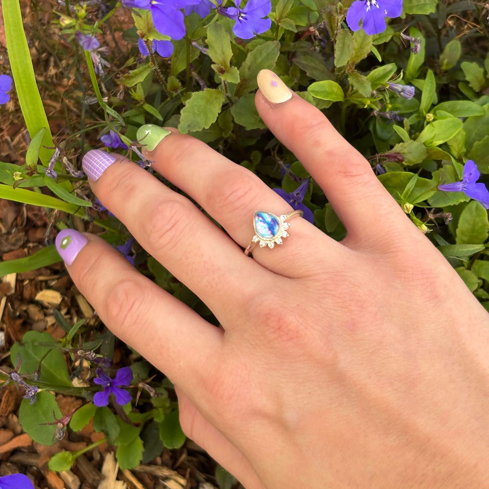 Sterling silver teardrop shaped ring with half halo of cubic zirconia stones and colon cancer cell image under resin pendant on model