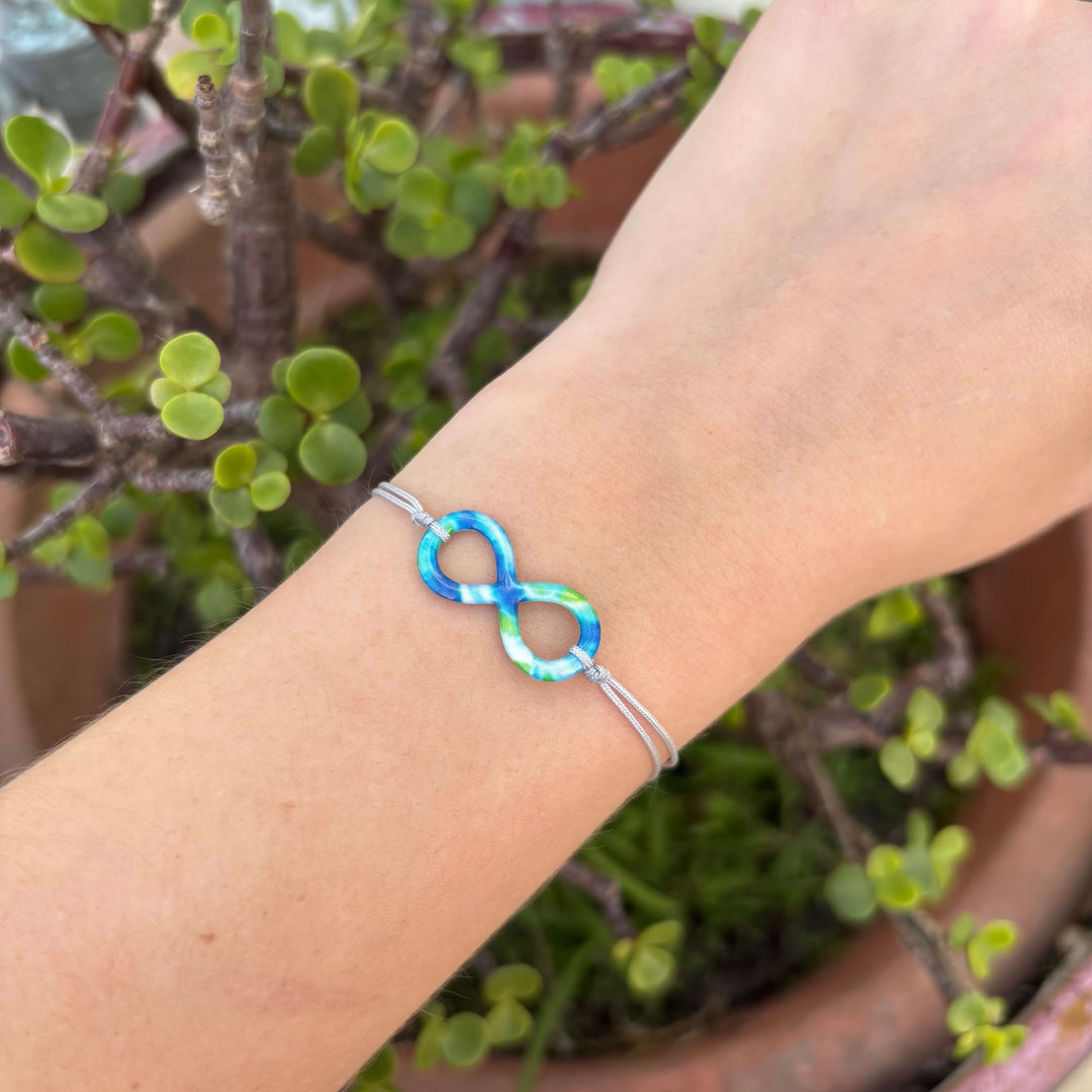 model wearing infinity symbol pendant with diabetes cell image in resin and adjustable gray cord with sterling silver slide bead