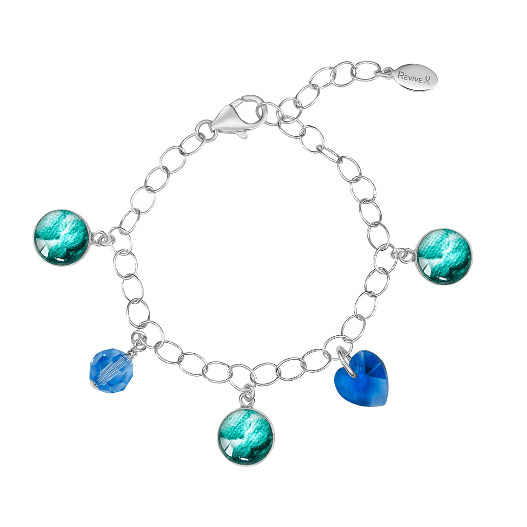 Silver bracelet with teal embryo images with blue crystals on a white background