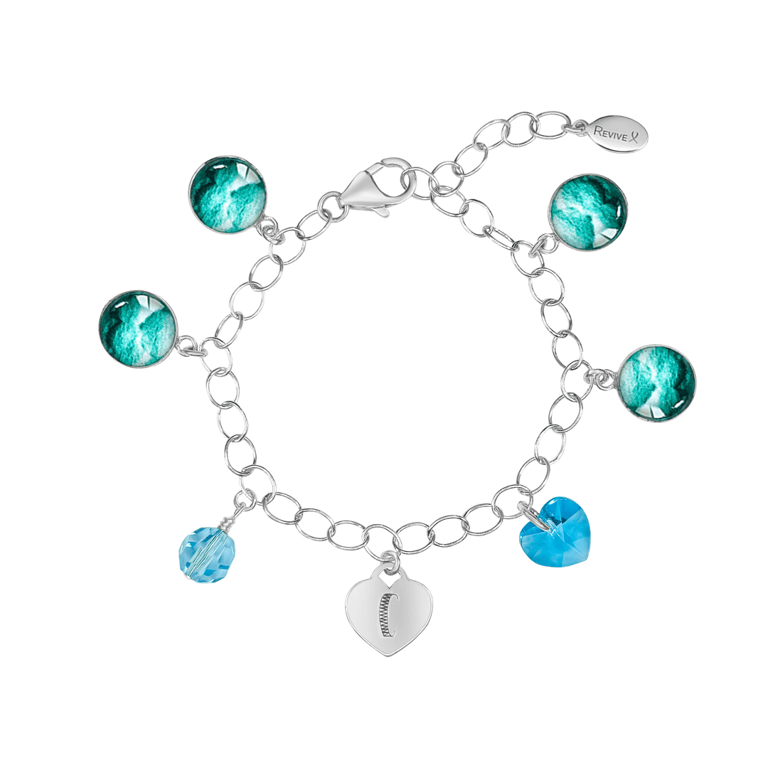 Silver bracelet with teal embryo images with blue crystals and a heart-shaped charm engraved with "C" on a white background