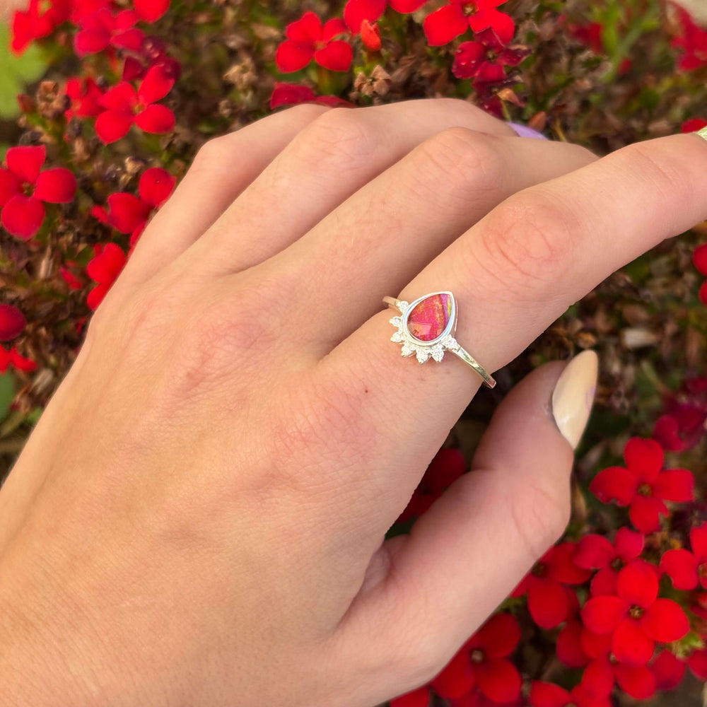 Sterling silver teardrop shaped ring with half halo of cubic zirconia stones and heart disease cell image under resin pendant on model