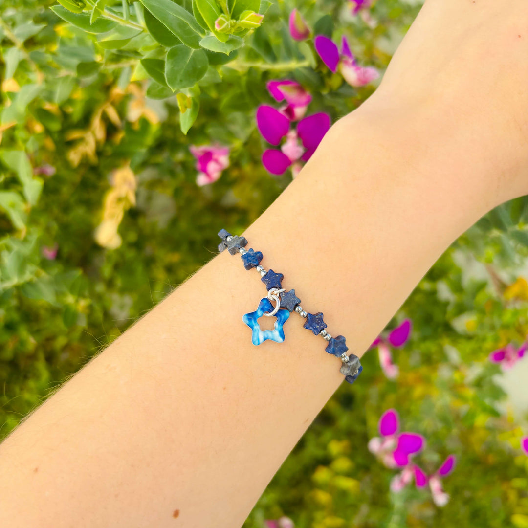 Bracelet with star-shaped beads on a wrist against a blurred natural background with flowers