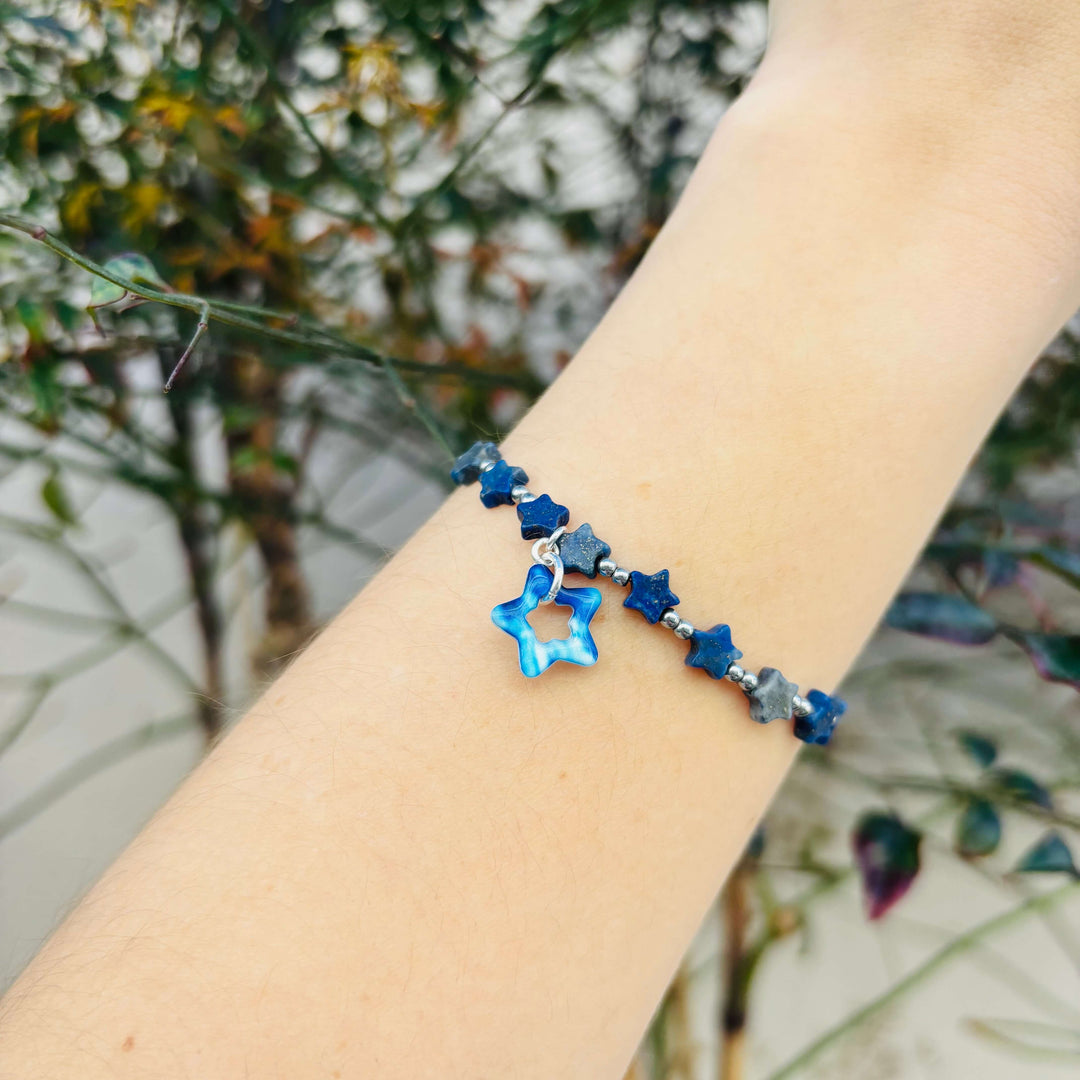 Bracelet with blue star-shaped beads on a wrist against a blurred natural background