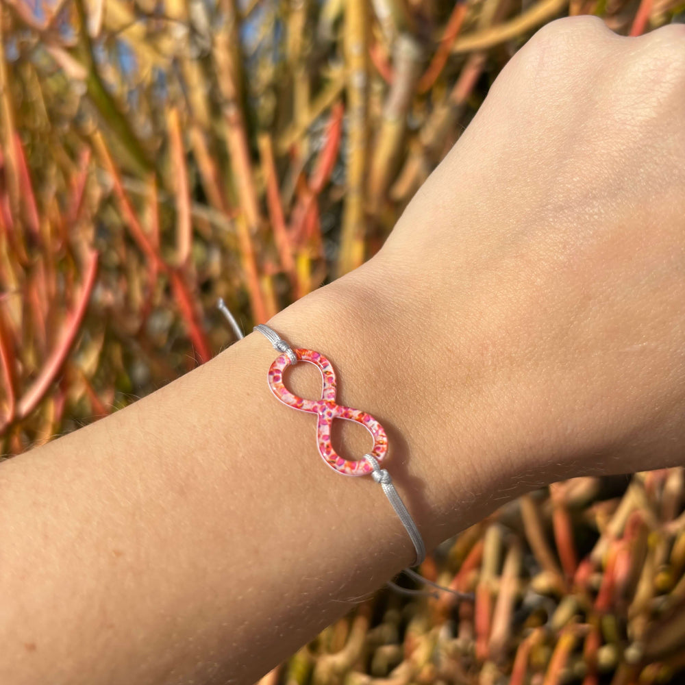 model wearing infinity pendant with orange leukemia cell image in resin on adjustable gray cord with Sterling silver slide bead