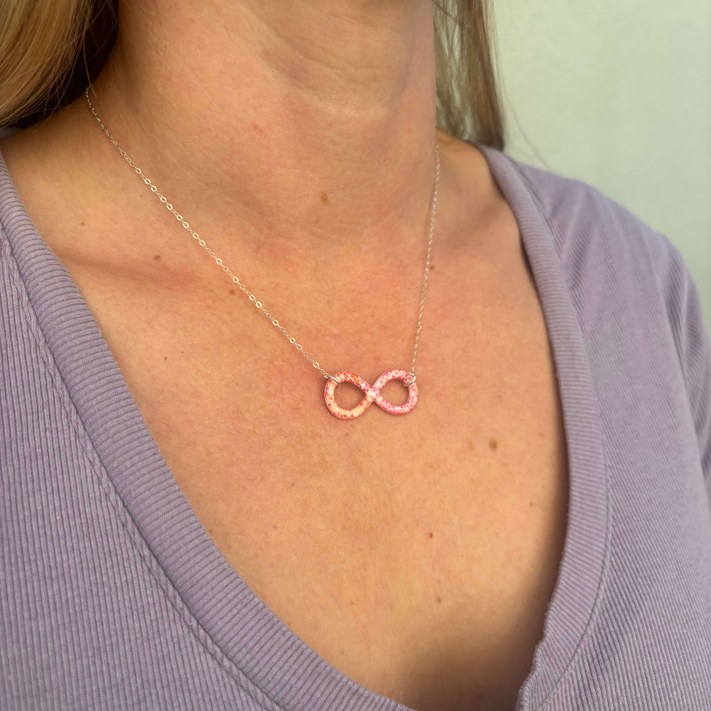 model wearing infinity pendant with orange leukemia cell image in resin on sterling silver adjustable chain