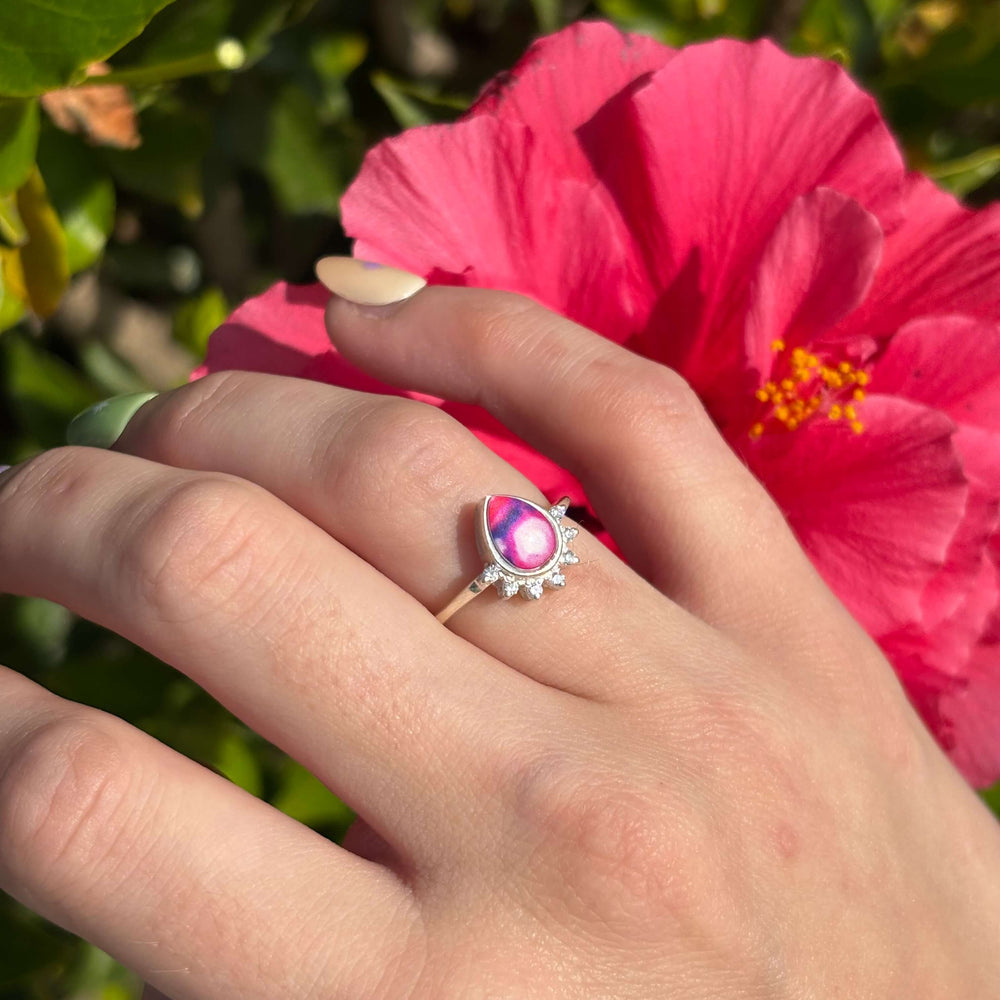Sterling silver teardrop shaped ring with half halo of cubic zirconia stones and lupus cell image under resin pendant on model