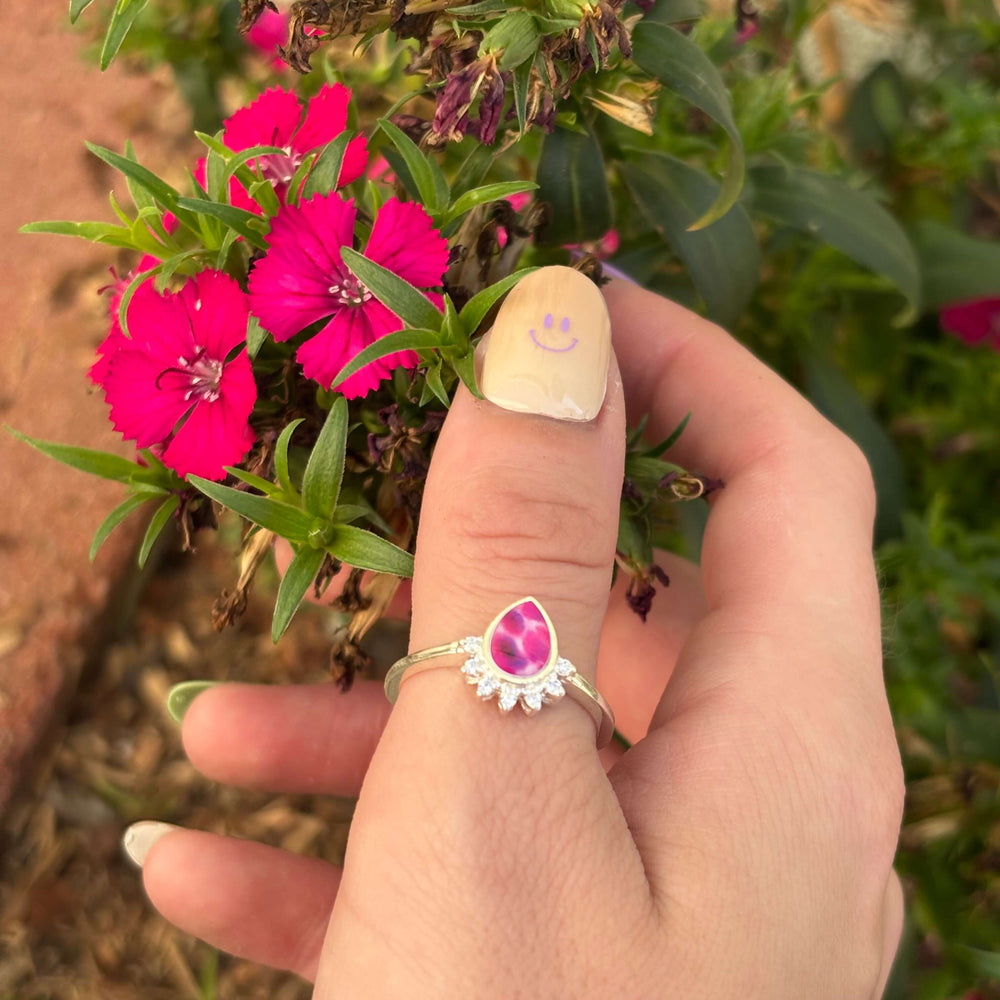 Sterling silver teardrop shaped ring with half halo of cubic zirconia stones and multiple myeloma cell image under resin pendant on model