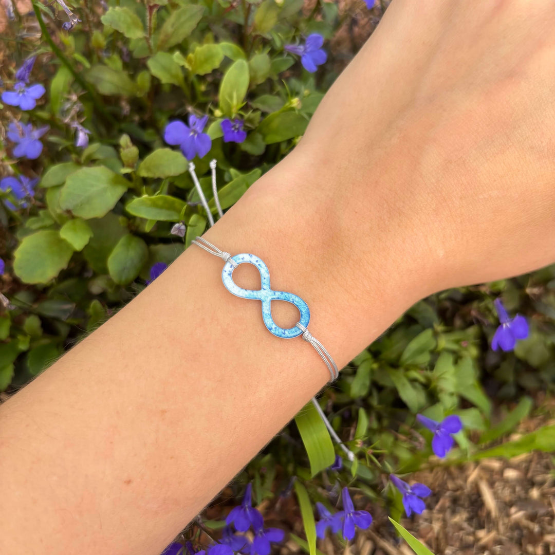 model wearing infinity pendant necklace with multiple sclerosis cell image in resin on adjustable gray cord with Sterling silver slide bead clasp  