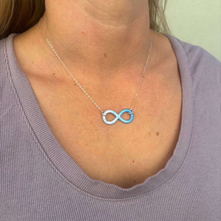 model wearing infinity pendant necklace with multiple sclerosis cell image in resin on sterling silver adjustable chain 