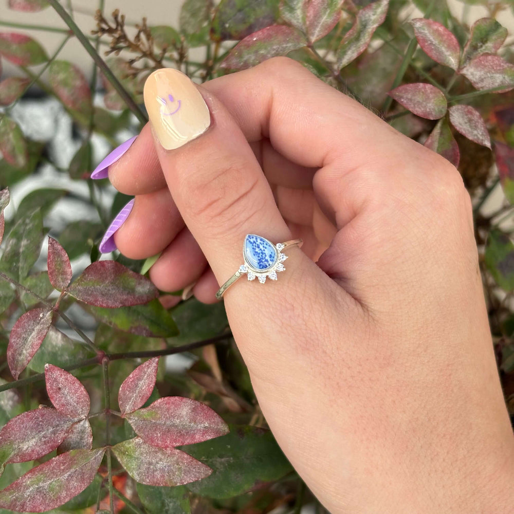 Sterling silver teardrop shaped ring with half halo of cubic zirconia stones and multiple sclerosis cell image under resin pendant on model
