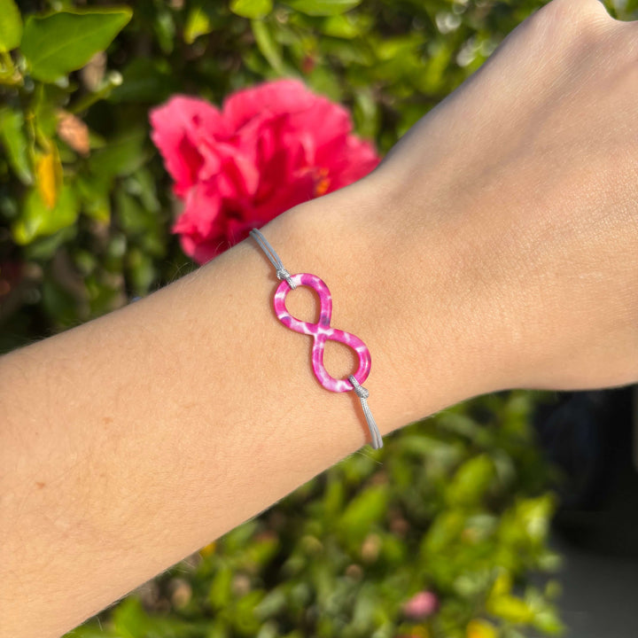 model wearing infinity pendant bracelet with multiple Myeloma cell image in resin on adjustable gray cord with Sterling silver slide bead 
