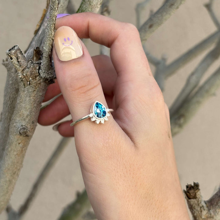 Sterling silver teardrop shaped ring with half halo of cubic zirconia stones and ovarian cancer cell image under resin pendant on model