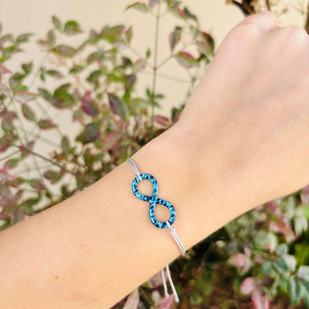 model wearing infinity pendant necklace with ovarian cancer cell image in resin on adjustable gray cord with Sterling silver slide bead 