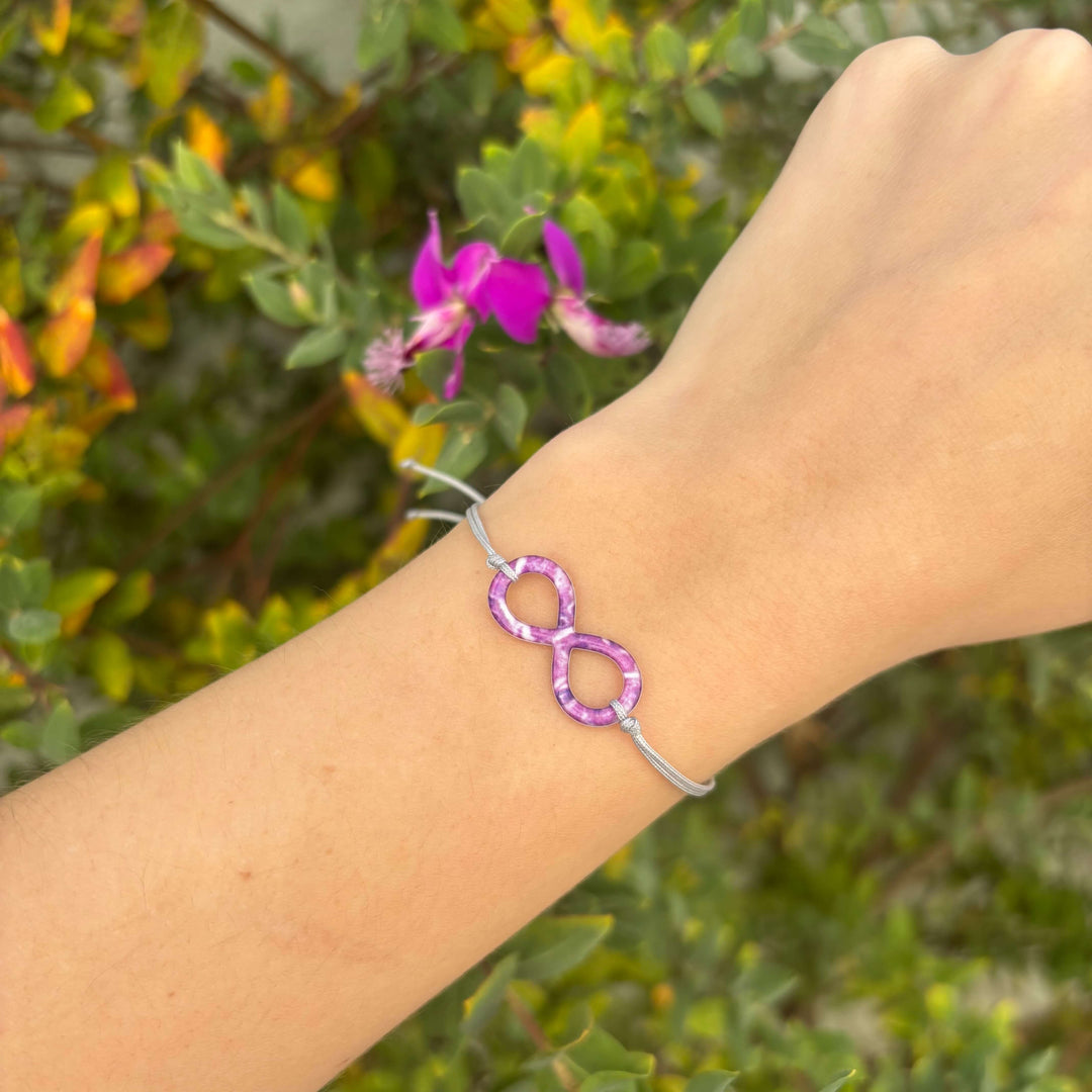 model wearing infinity pendant necklace with pancreatic cancer cell image in resin on adjustable gray cord with Sterling silver slide bead 