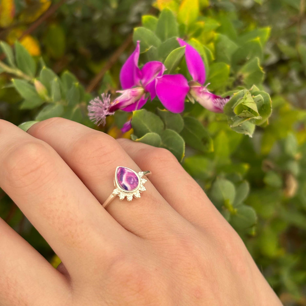 Sterling silver teardrop shaped ring with half halo of cubic zirconia stones and pancreatic cancer cell image under resin pendant on model