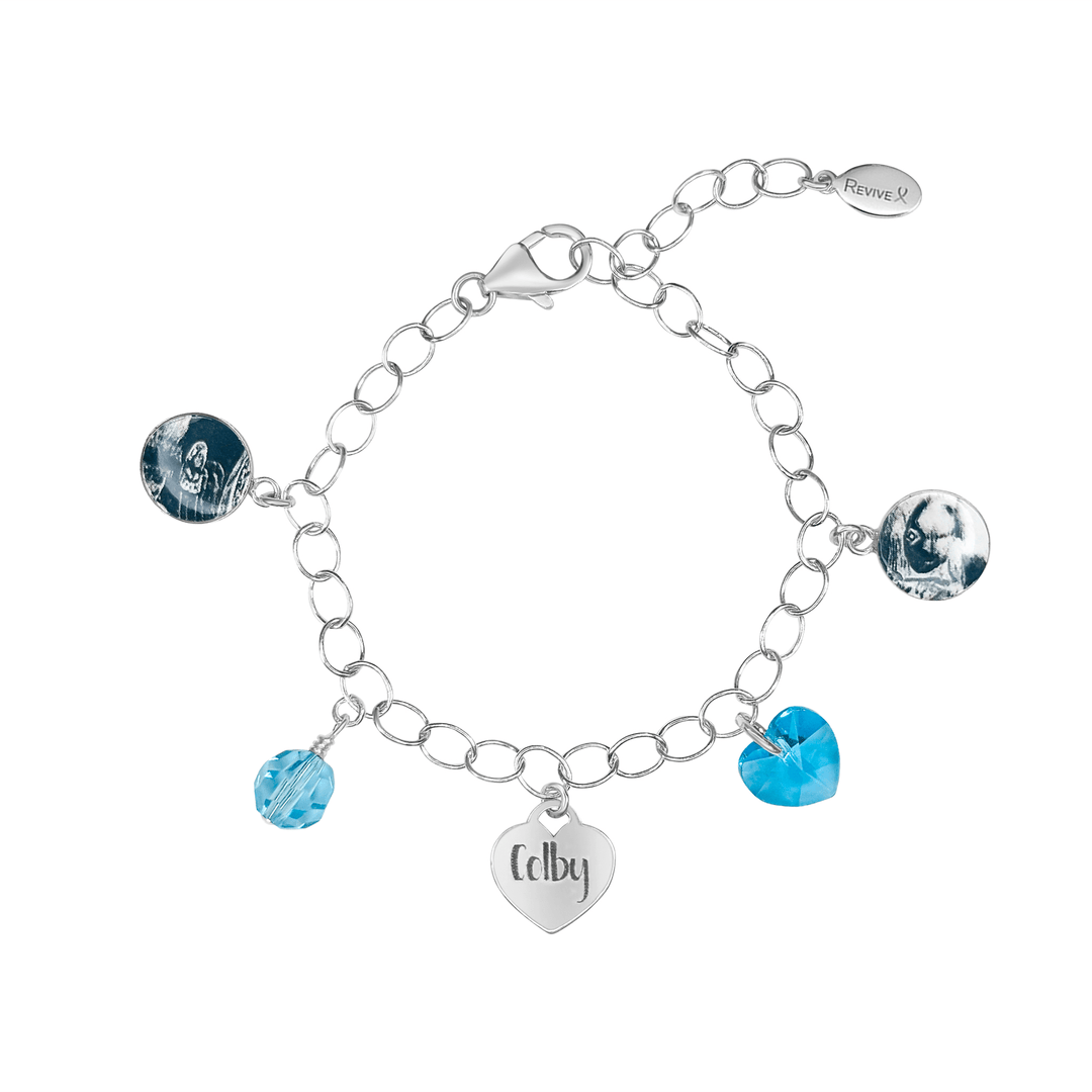 Silver bracelet with grayscale sonogram pendants with blue birthstone crystals and a heart-shaped charm engraved with "Colby"on a white background