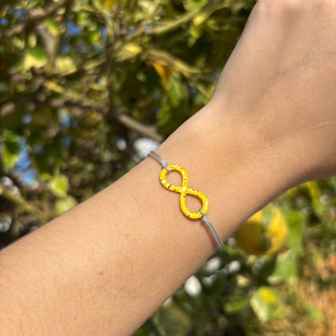 model wearing infinity pendant necklace with sarcoma cell image in resin on adjustable gray cord with Sterling silver slide bead 