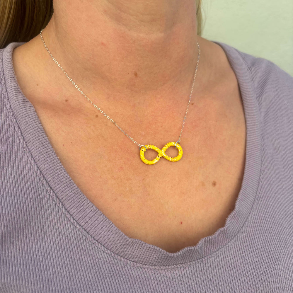model wearing infinity pendant necklace with sarcoma cell image in resin on Sterling silver adjustable chain 