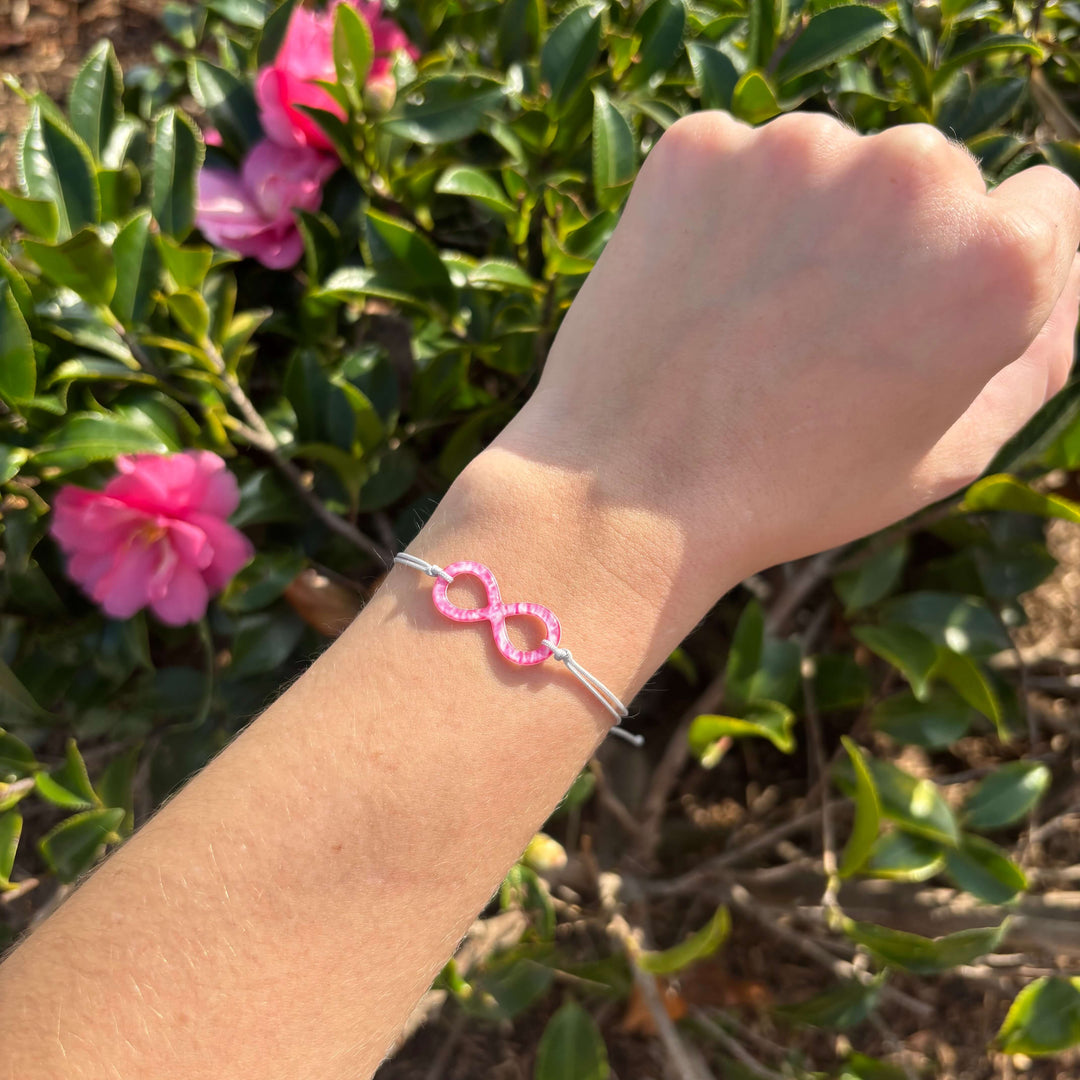 model wearing pink breast cancer cell image infinity symbol pendant with resin and gray adjustable cord with Sterling silver slide bead. 