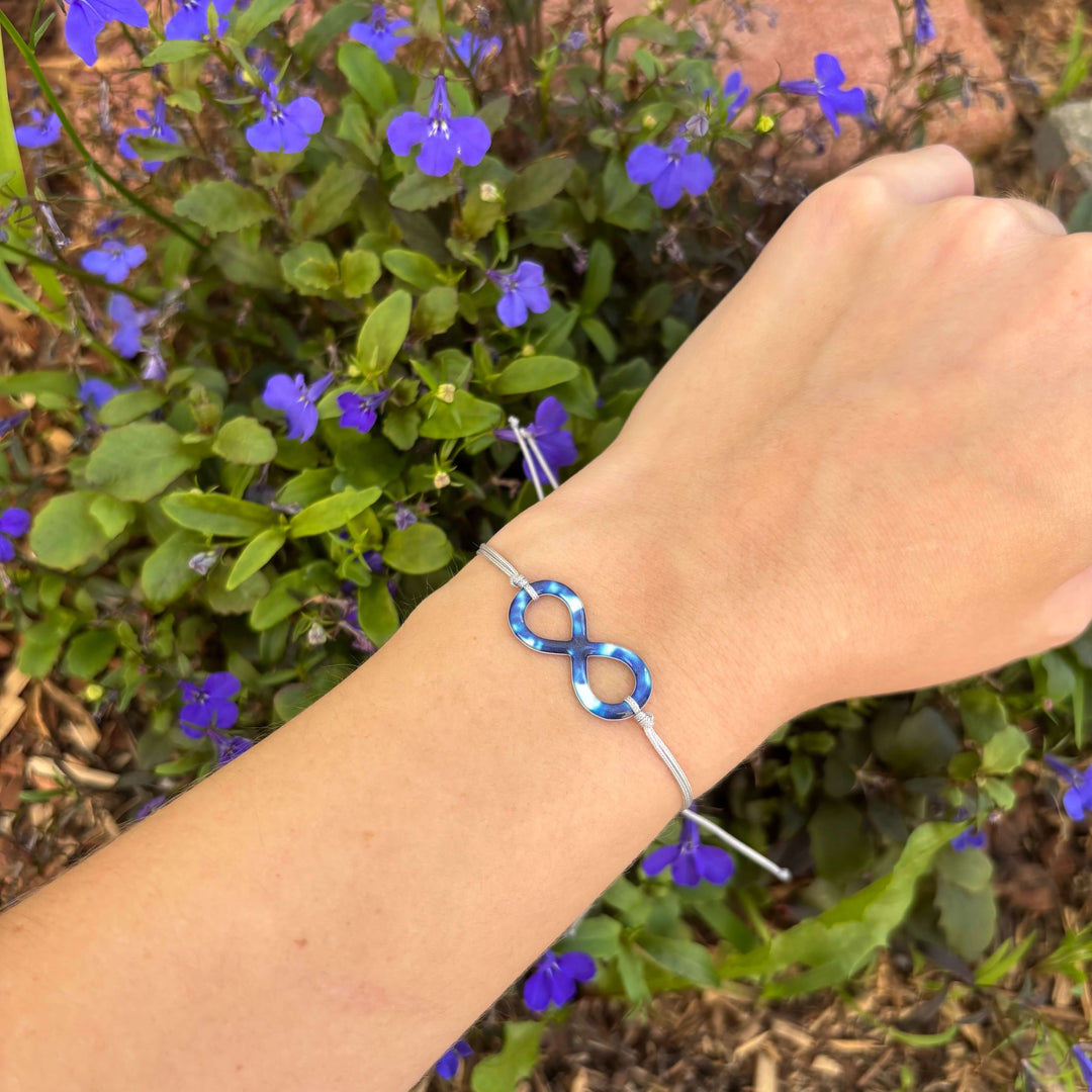 model wearing neuroblastoma cell image in resin shaped like an infinity symbol on adjustable gray cord with Sterling silver slide bead 