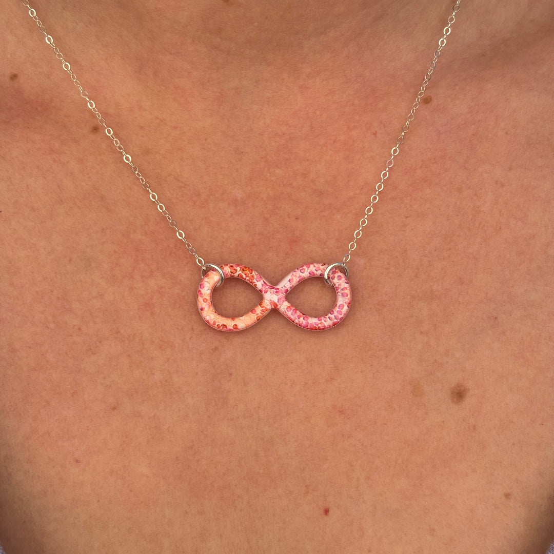 close up of model wearing infinity pendant with orange leukemia cell image in resin on sterling silver adjustable chain