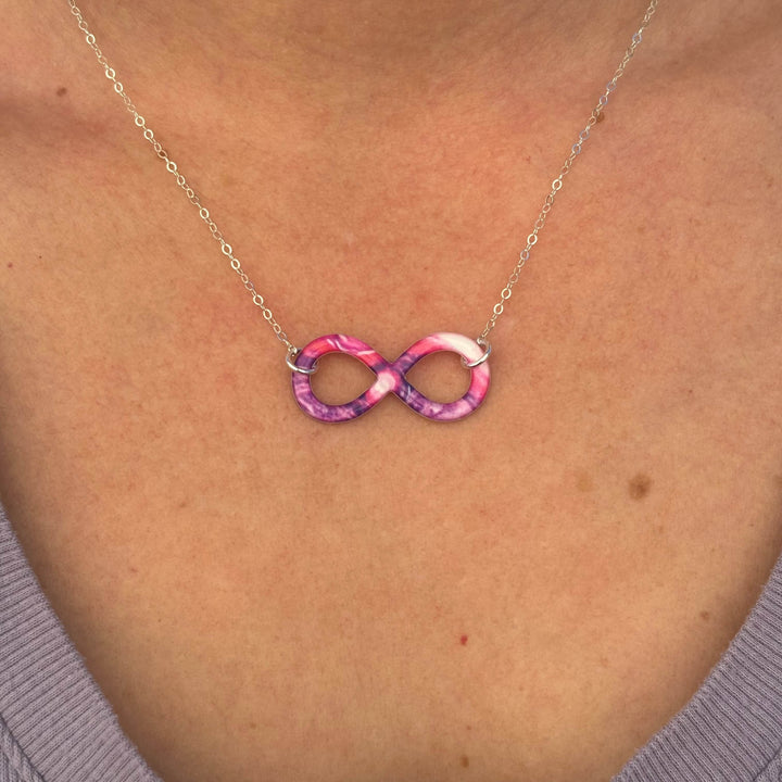 close up of model wearing infinity pendant necklace with lupus cell image in resin on Sterling silver chain 