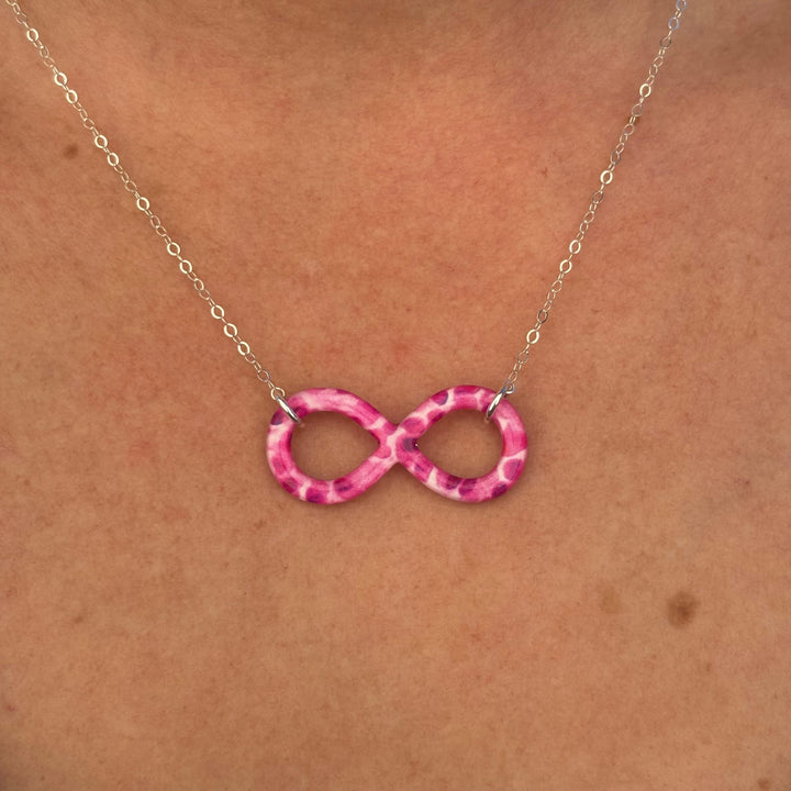 close up of model wearing infinity pendant necklace with multiple Myeloma cell image in resin on Sterling silver adjustable chain 