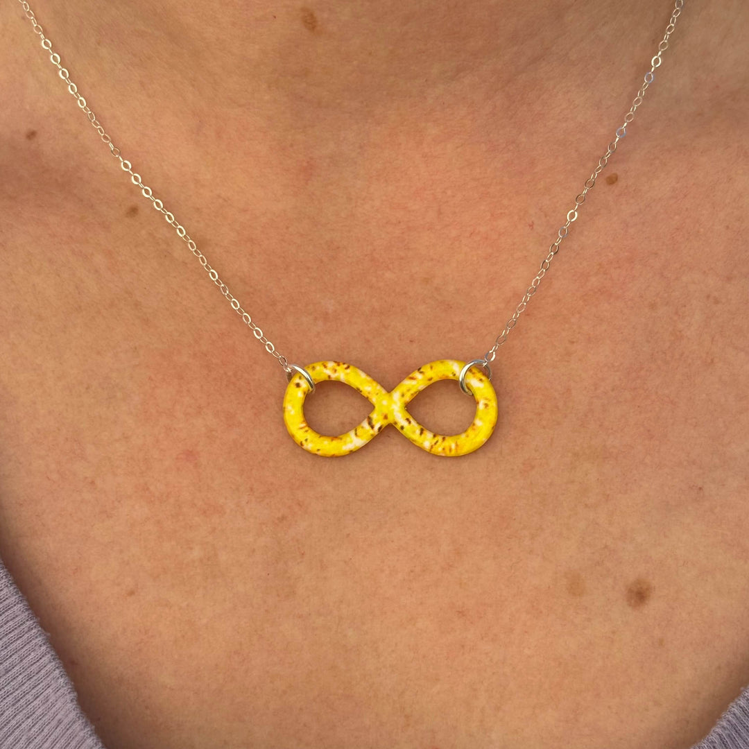 close up of model wearing infinity pendant necklace with sarcoma cell image in resin on Sterling silver adjustable chain 