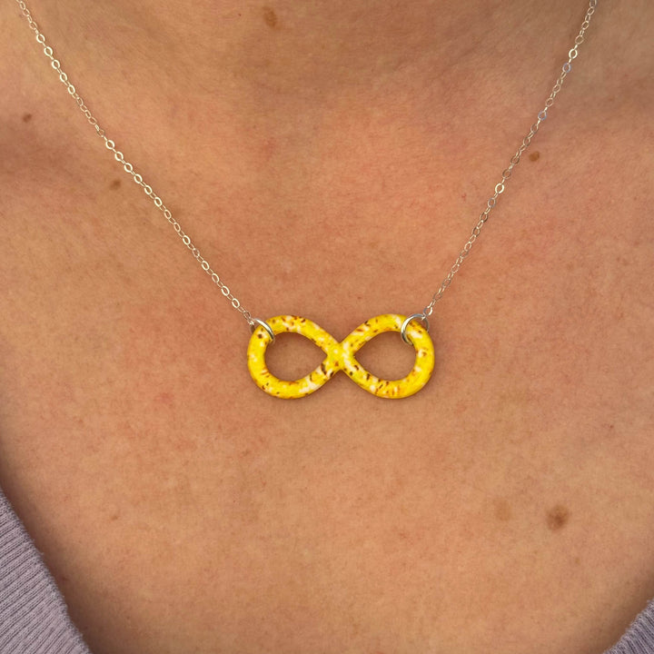 close up of model wearing infinity pendant necklace with sarcoma cell image in resin on Sterling silver adjustable chain 