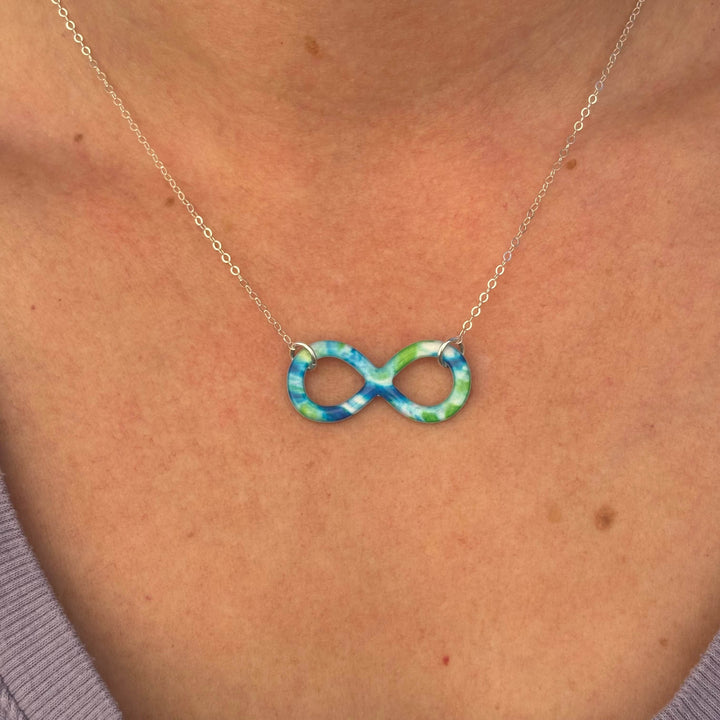 close up of model wearing infinity symbol pendant with diabetes cell image in resin and sterling silver chain