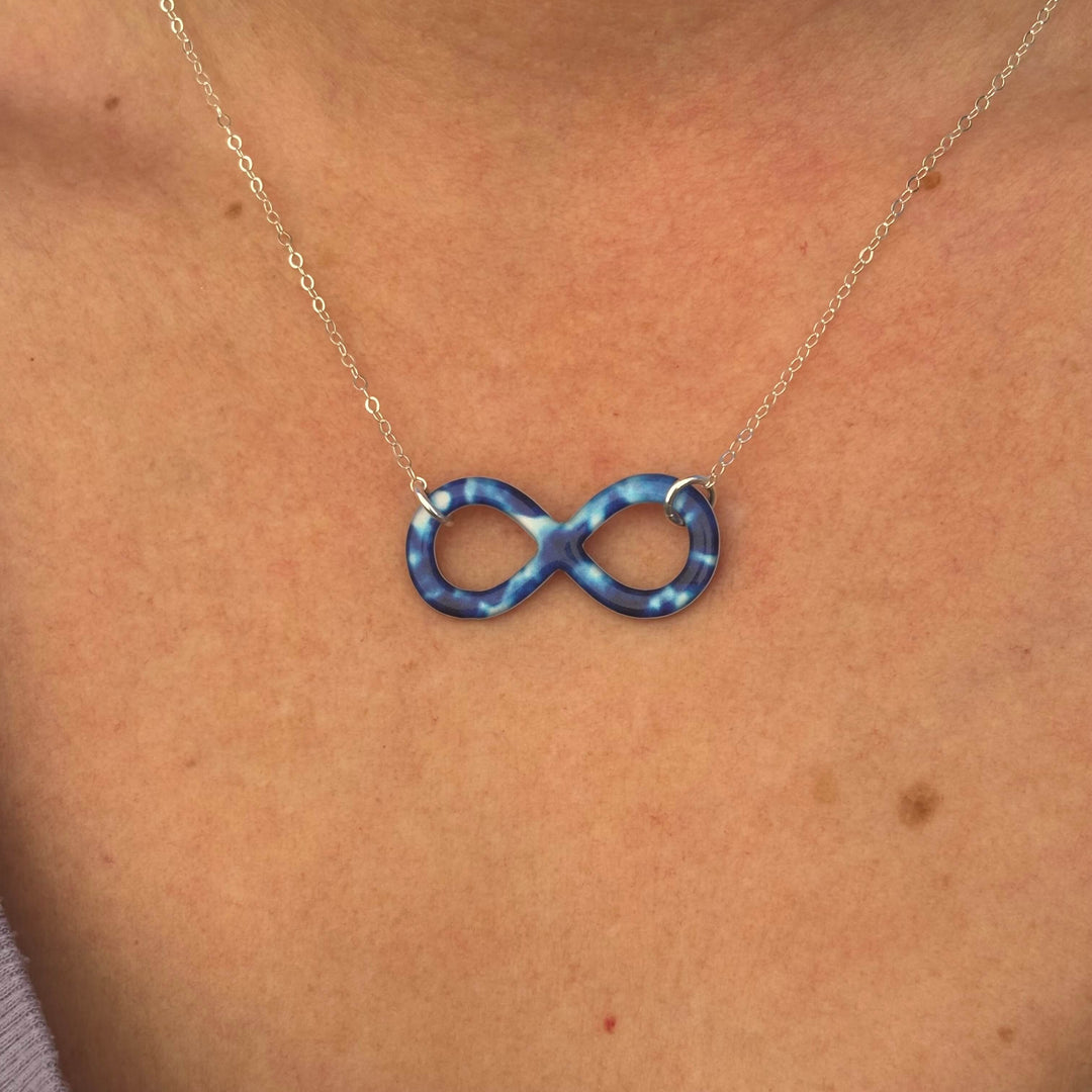close up of model wearing childhood cancer cell image infinity symbol pendant with resin and Sterling silver chain necklace