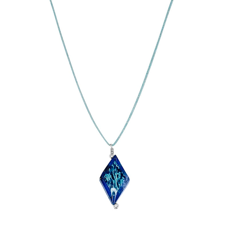 close up of diamond shaped dark blue lapis stone pendant necklace on teal cord featuring ovarian cancer cell image in resin
