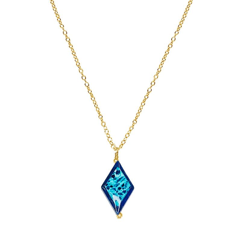 close up of diamond shaped dark blue lapis stone pendant necklace on gold filled chain featuring ovarian cancer cell image in resin
