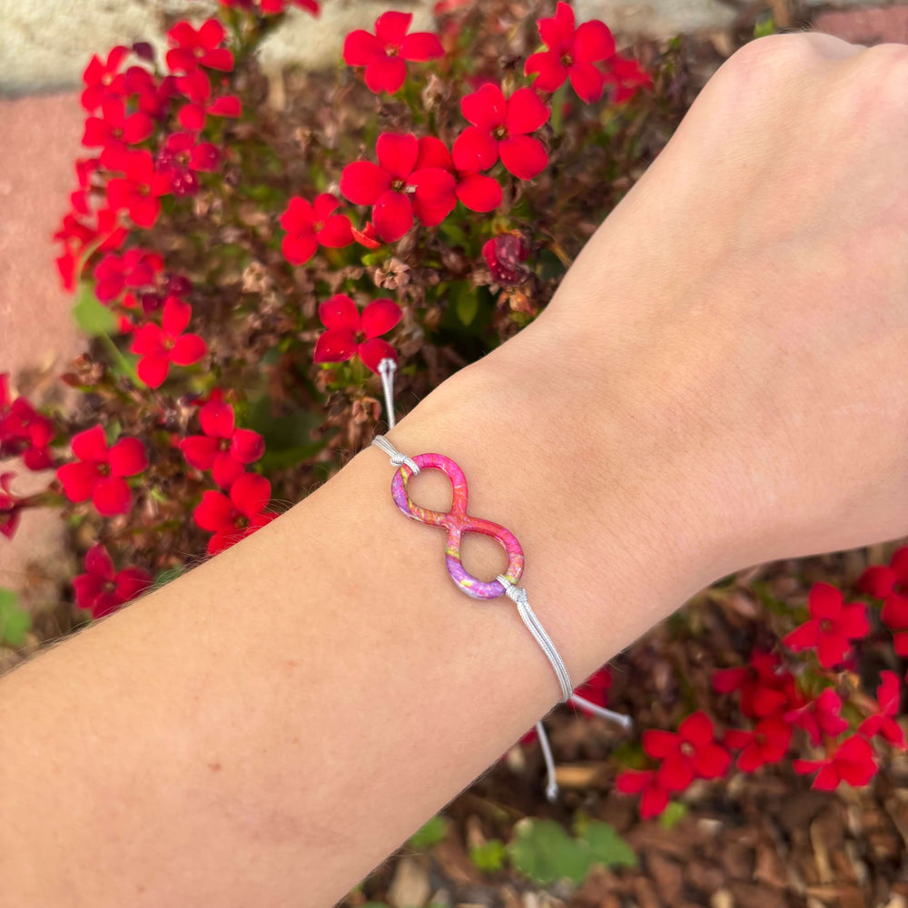 model wearing infinity symbol pendant with heart disease cell image in resin with adjustable gray cord and Sterling silver slide bead 
