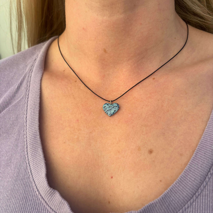 model wearing heart shaped necklace with ovarian cancer awareness cell image in resin pendant on adjustable black cord