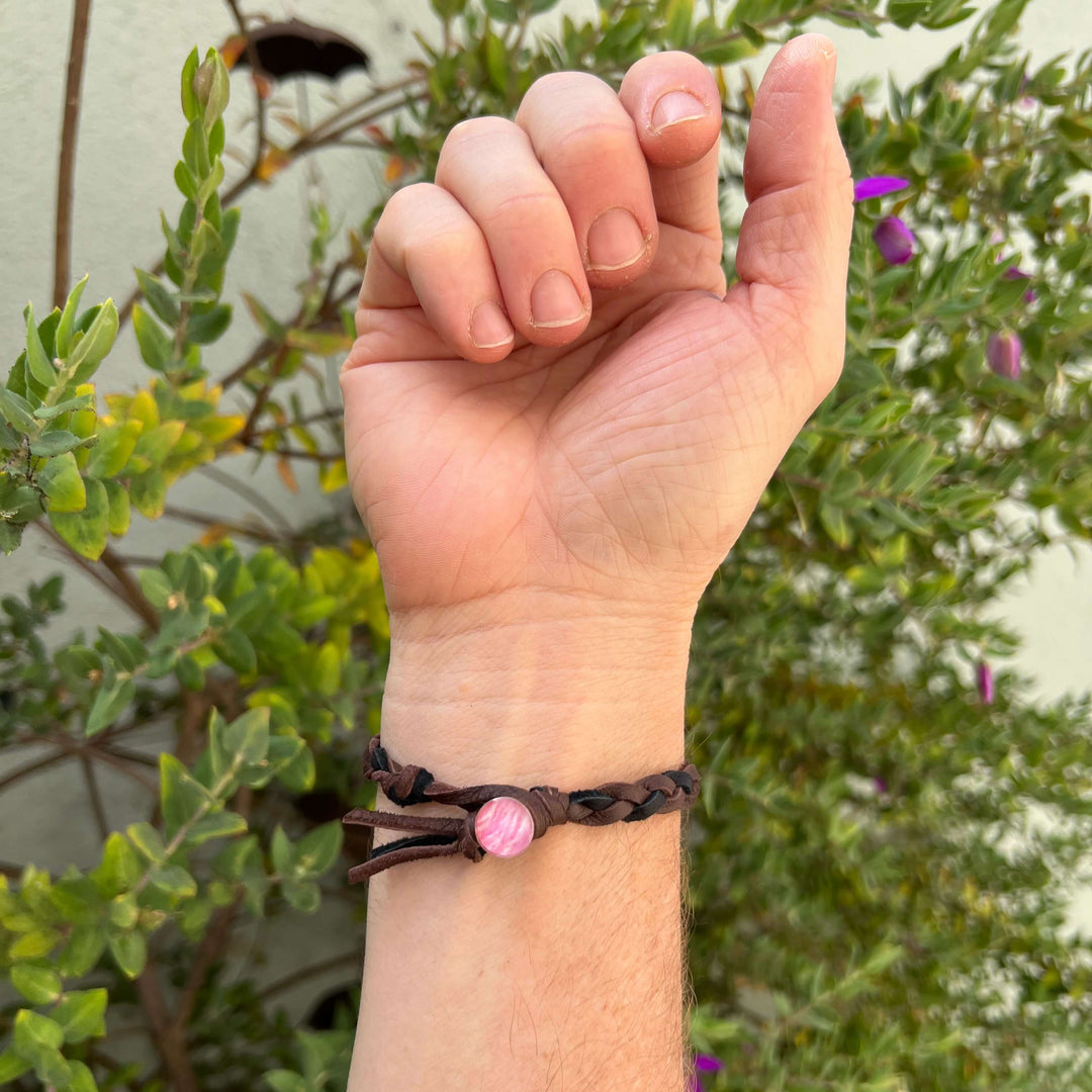 back of wrist view of man wearing brown and black guys leather bracelet with round breast cancer cell image in resin pendant