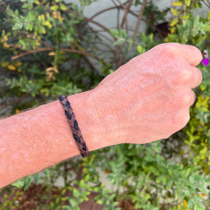 top view of man wearing brown and black guys leather bracelet with round breast cancer cell image in resin pendant