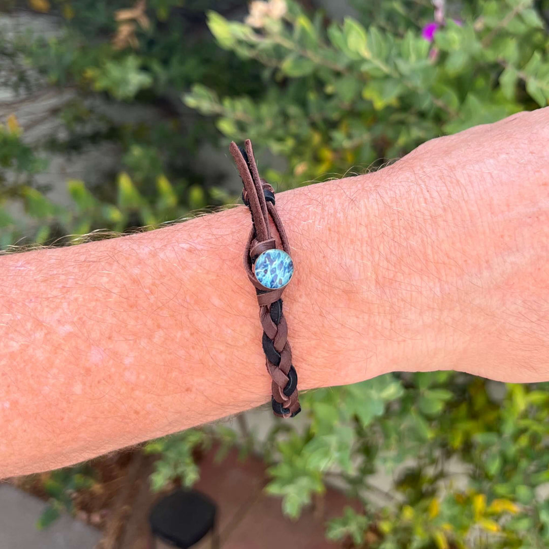 close up of man wearing brown and black guys leather bracelet with round ovarian cancer cell image in resin pendant