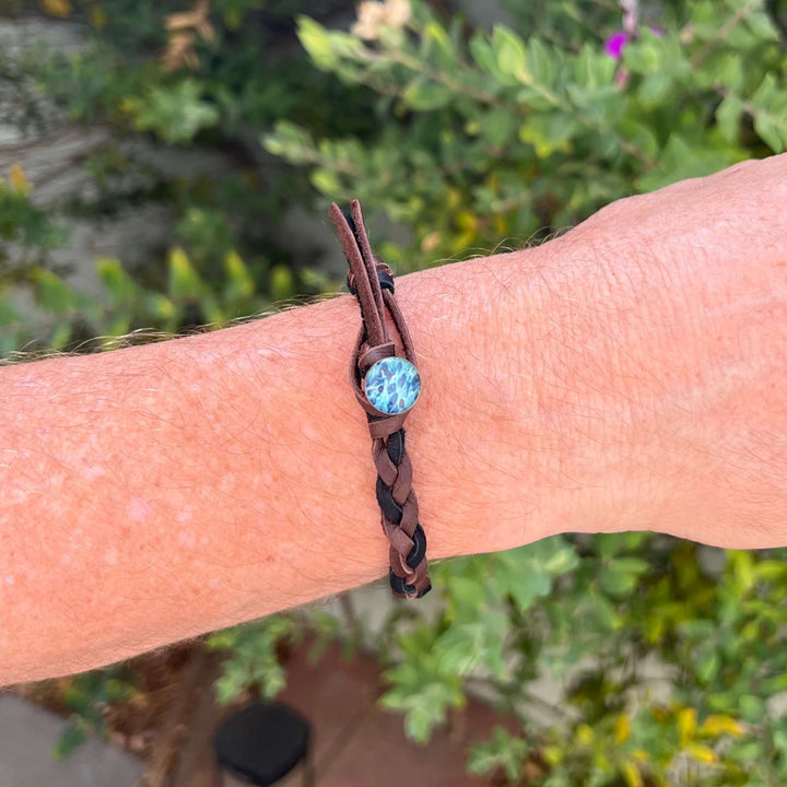 close up of man wearing brown and black guys leather bracelet with round ovarian cancer cell image in resin pendant