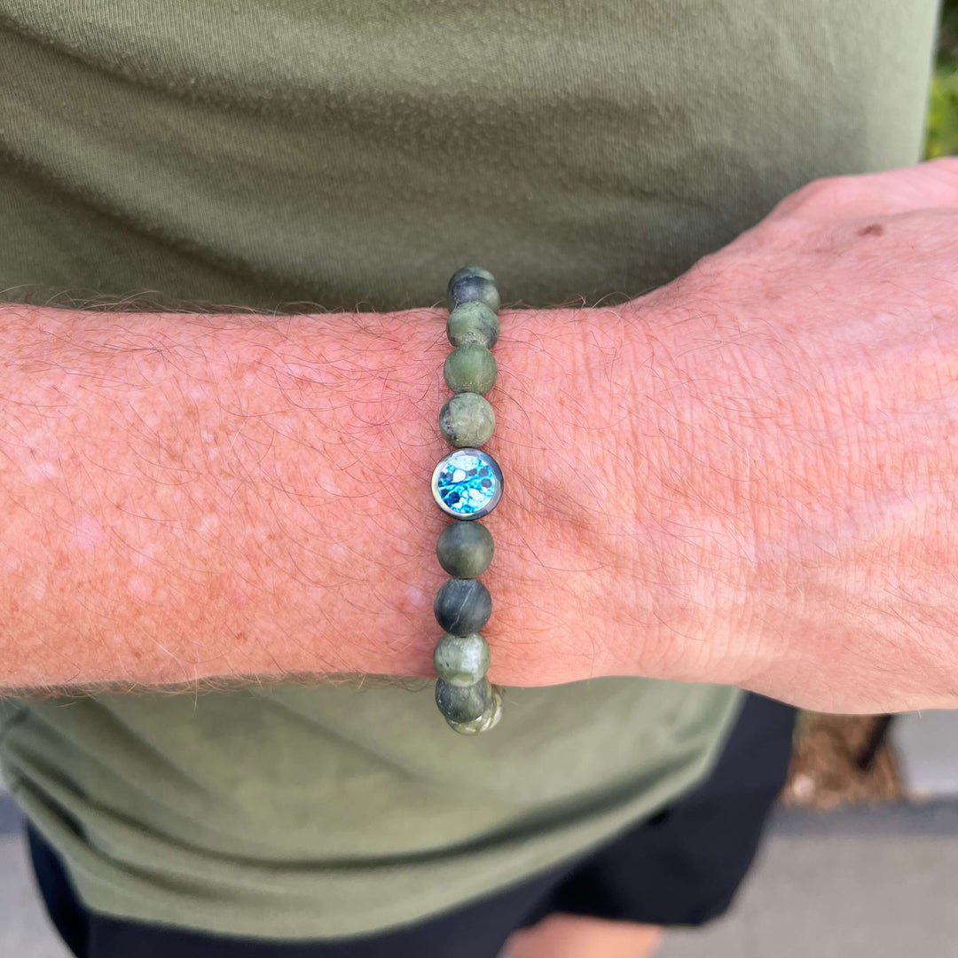 close up of man wearing mens jade bracelet with ovarian cancer cell image in resin pendant on stretch cord