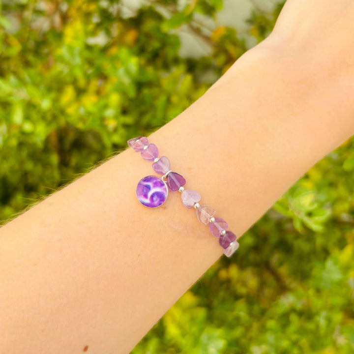 purple heart shaped amethyst beads and small Sterling silver spacer beads on stretch cord with round pancreatic cancer cell image in resin pendant on model