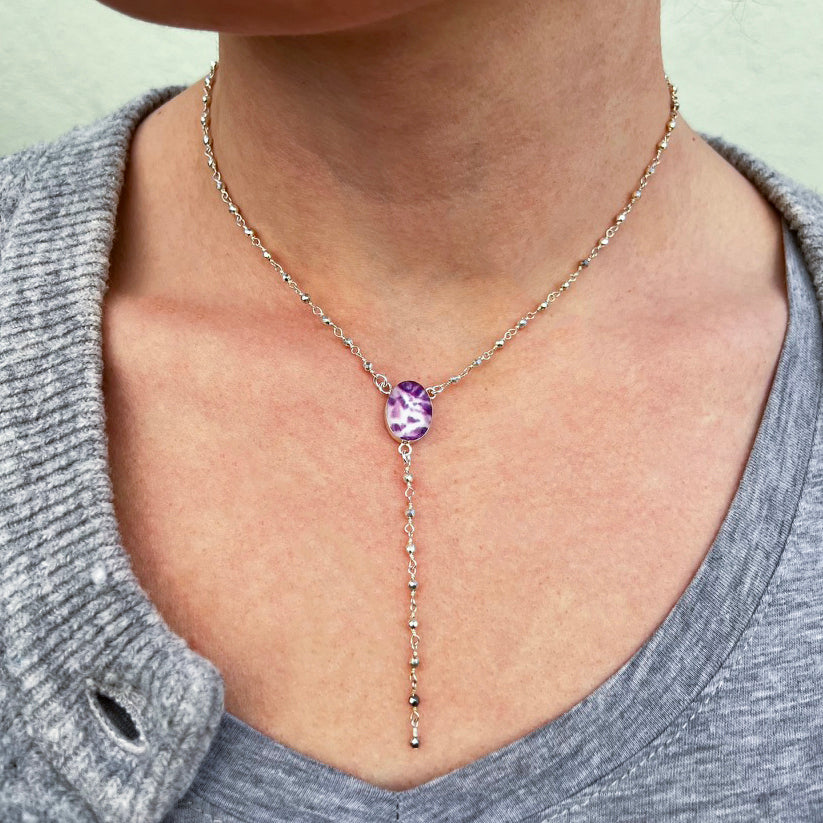 model wearing y necklace for pancreatic cancer with cell image resin pendant and rosary style silver pyrite linked chain