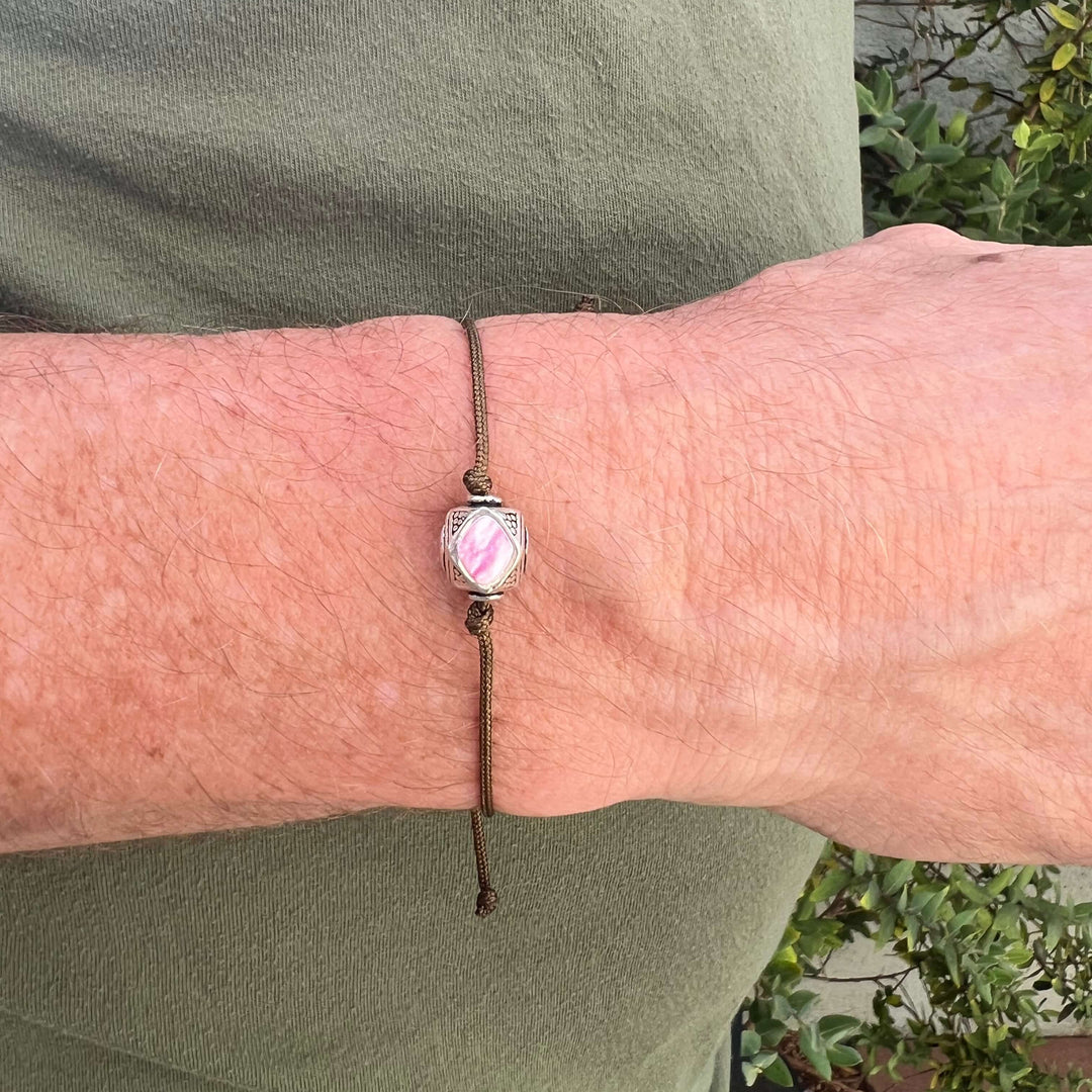 close up of model wearing mens Sterling silver breast cancer cell image in resin pendant on brown adjustable cord